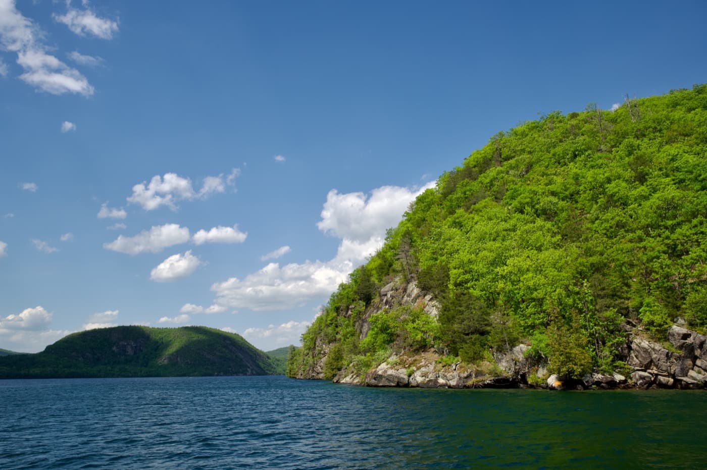 Looking north toward Rogers Rock, forested cliffs rising from the deep blue water